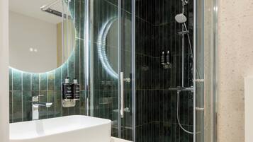 A modern bathroom with a glass-enclosed shower, a white sink, and a mirror above it.