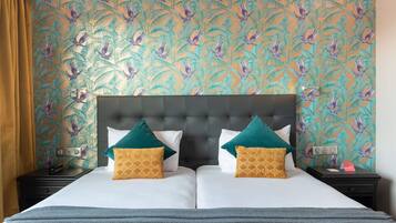 A double bed with a tufted headboard, two nightstands, and patterned wallpaper.