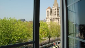 Une vue d’une cathédrale à travers une fenêtre, avec des arbres au premier plan.