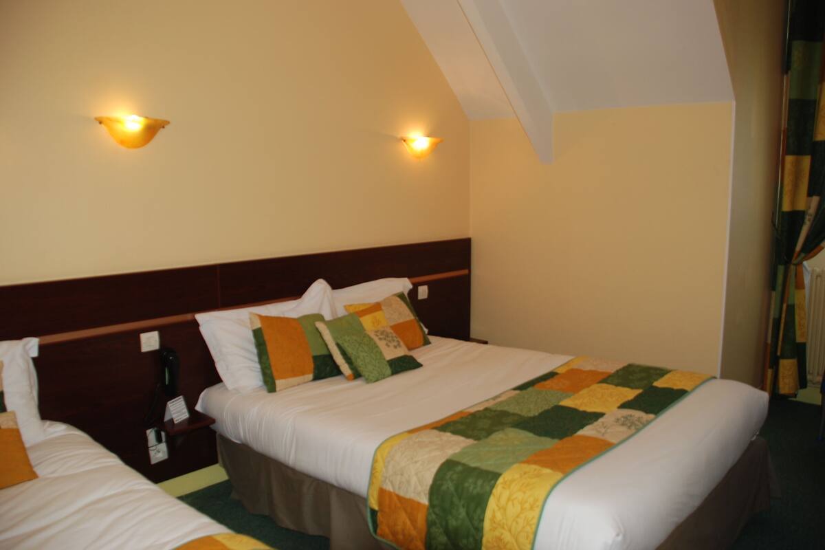 Ein Hotelzimmer mit zwei Betten, einem Holzkopfschild und zwei Wandleuchten.