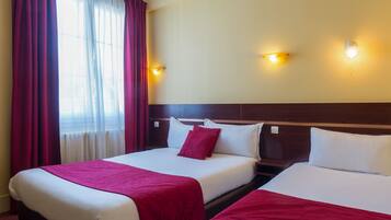 A hotel room with two beds, red curtains, and wall-mounted lights.