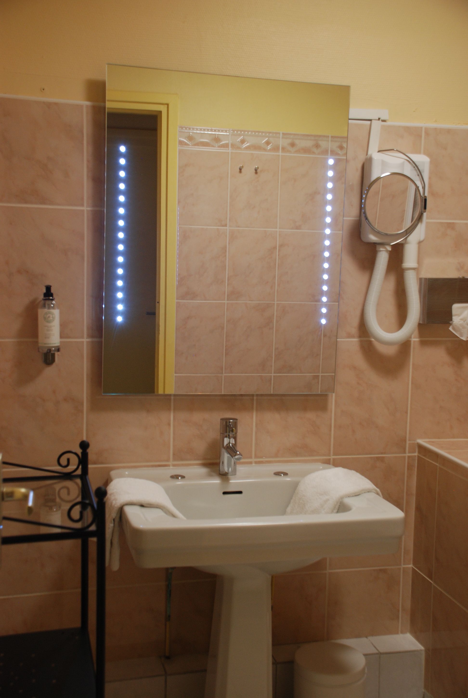 A bathroom with a sink, mirror, and lights.