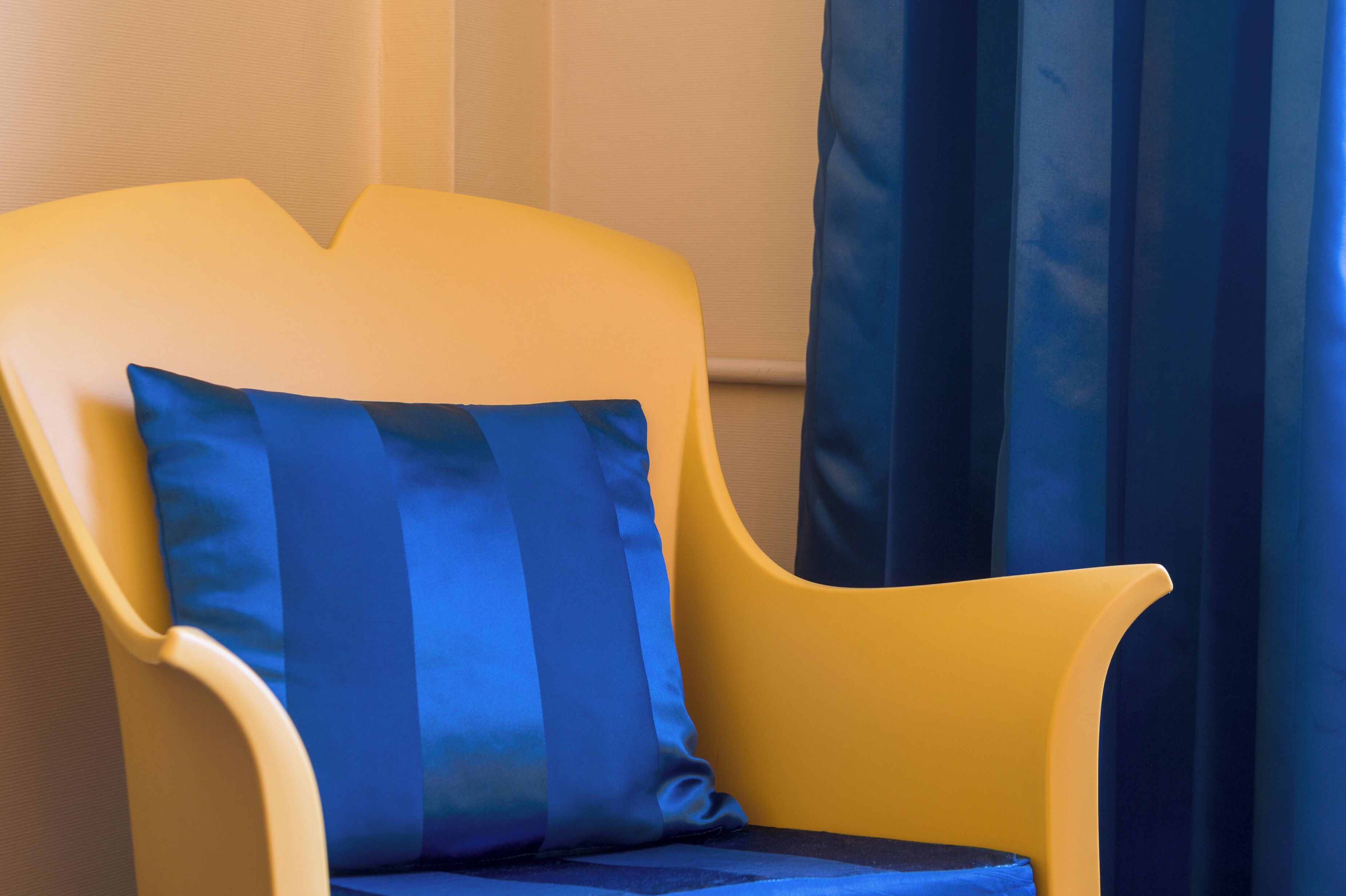 Un sillón amarillo con un cojín azul.