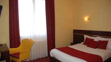 Ein Hotelzimmer mit Bett, Stuhl, Schreibtisch und einem fensterbepflanzten Fenster.