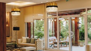 A spacious lobby with a marble floor, a sofa, a coffee table, and a chandelier. - Hotel Corsica & Spa Serena (Calvi)
