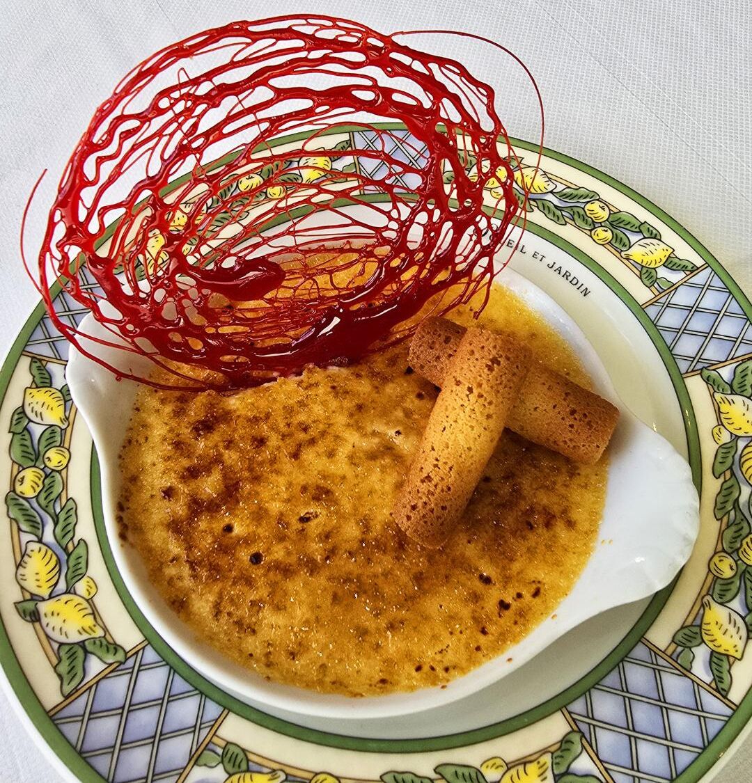 A bowl of custard with a rolled pastry on a patterned plate.