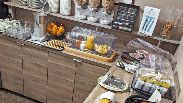 Ein reichhaltiges Frühstücksbuffet mit verschiedenen Speisen, darunter Brot, Gebäck und Getränke.