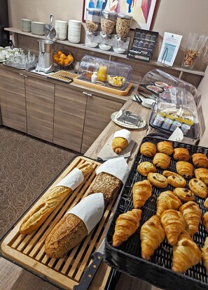 A breakfast buffet with various food items, including bread, pastries, and beverages. - Soleil et Jardin (Solaize)