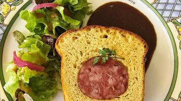 Um prato com sanduíche, salada e molho.