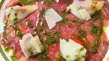A plate of Carpaccio de boeuf, coques de parmesan, and poivrons confits, pistou.