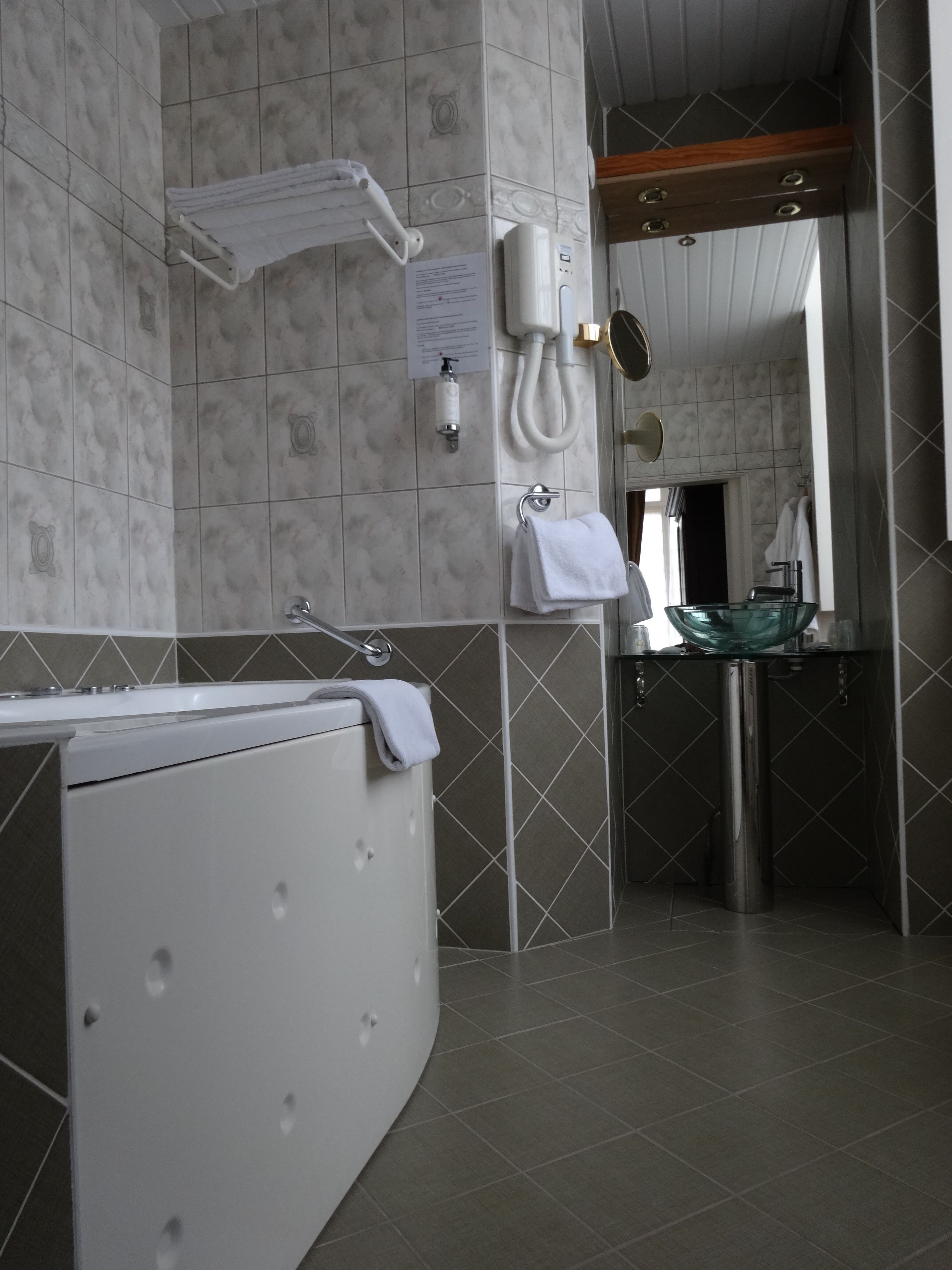 Un baño moderno con una bañera independiente, un lavabo de vidrio y un perchero para toallas.