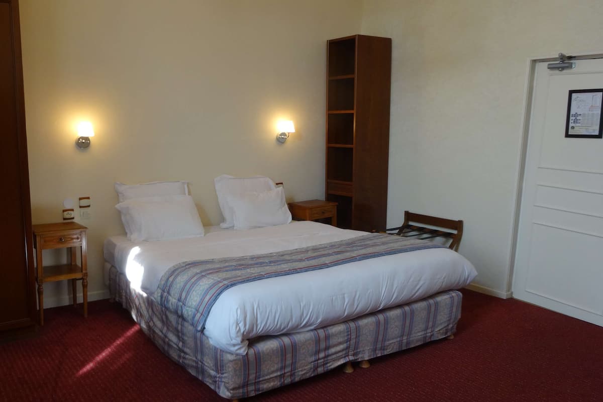 A bedroom with a bed, two bedside tables, a wooden wardrobe, and a door.