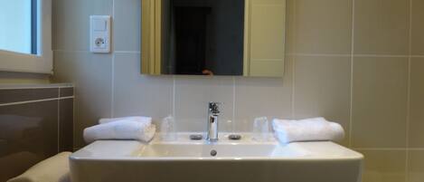 A bathroom with a large sink, two towels, a mirror, and a window.