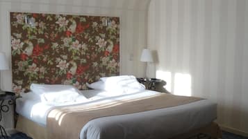 A hotel room with a bed, a bedside table, a lamp, a chair, and a small round table.