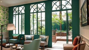 A room with a checkered floor, green paneled windows, and a view of the outside garden. - Hôtel Serotel Lutèce (Paris)