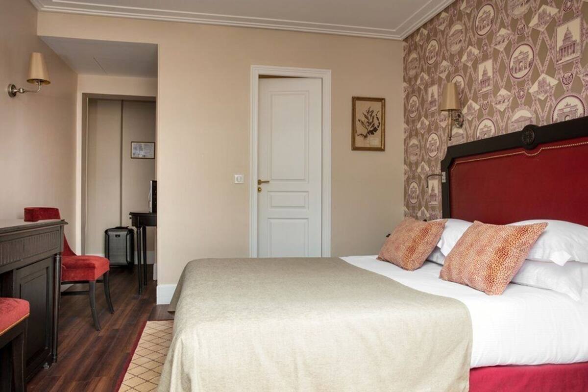 A hotel room with a bed, a desk, a chair, and a wardrobe.