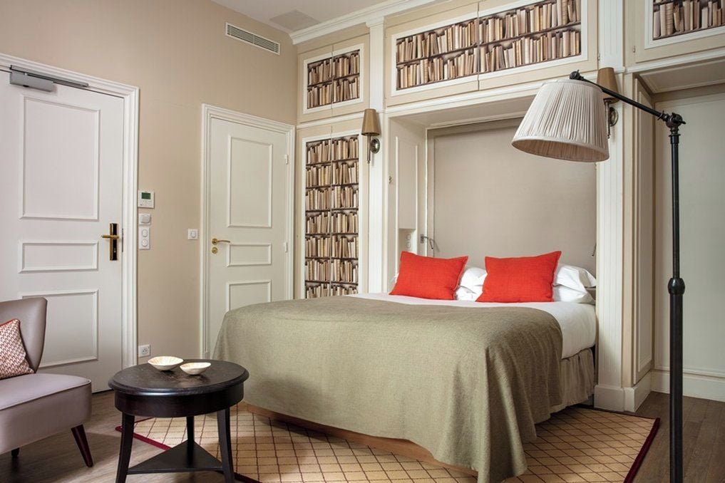 Une chambre d’hôtel avec un lit, une table de chevet, une chaise et une bibliothèque.