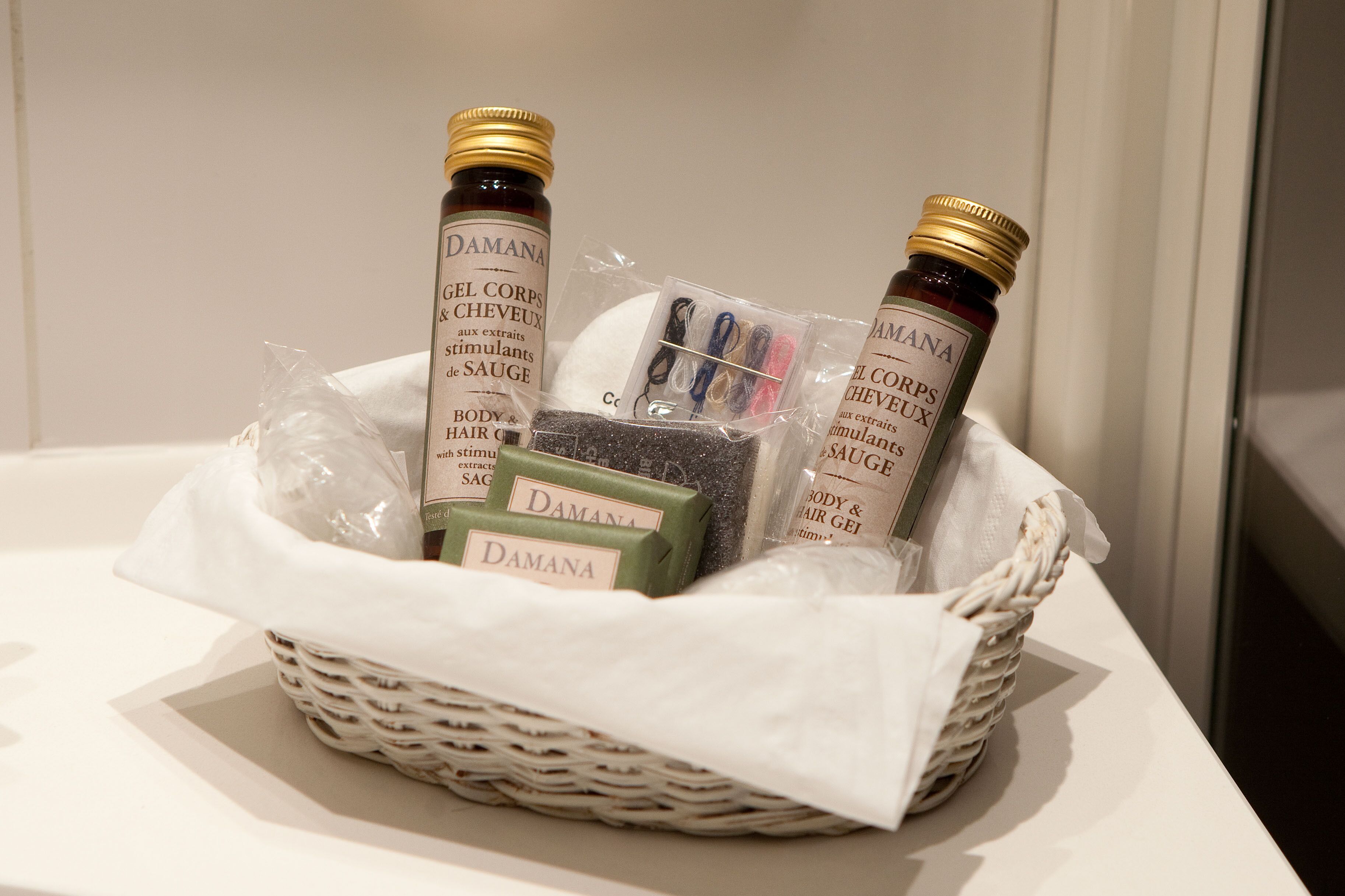 A wicker basket containing various items including bottles labeled 'Damana' and a green soap bar.