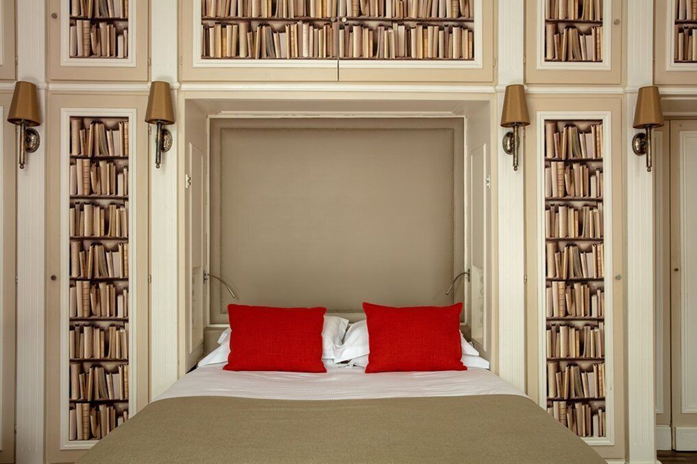 Une chambre à coucher avec un grand lit, deux oreillers rouges et des étagères de chaque côté.
