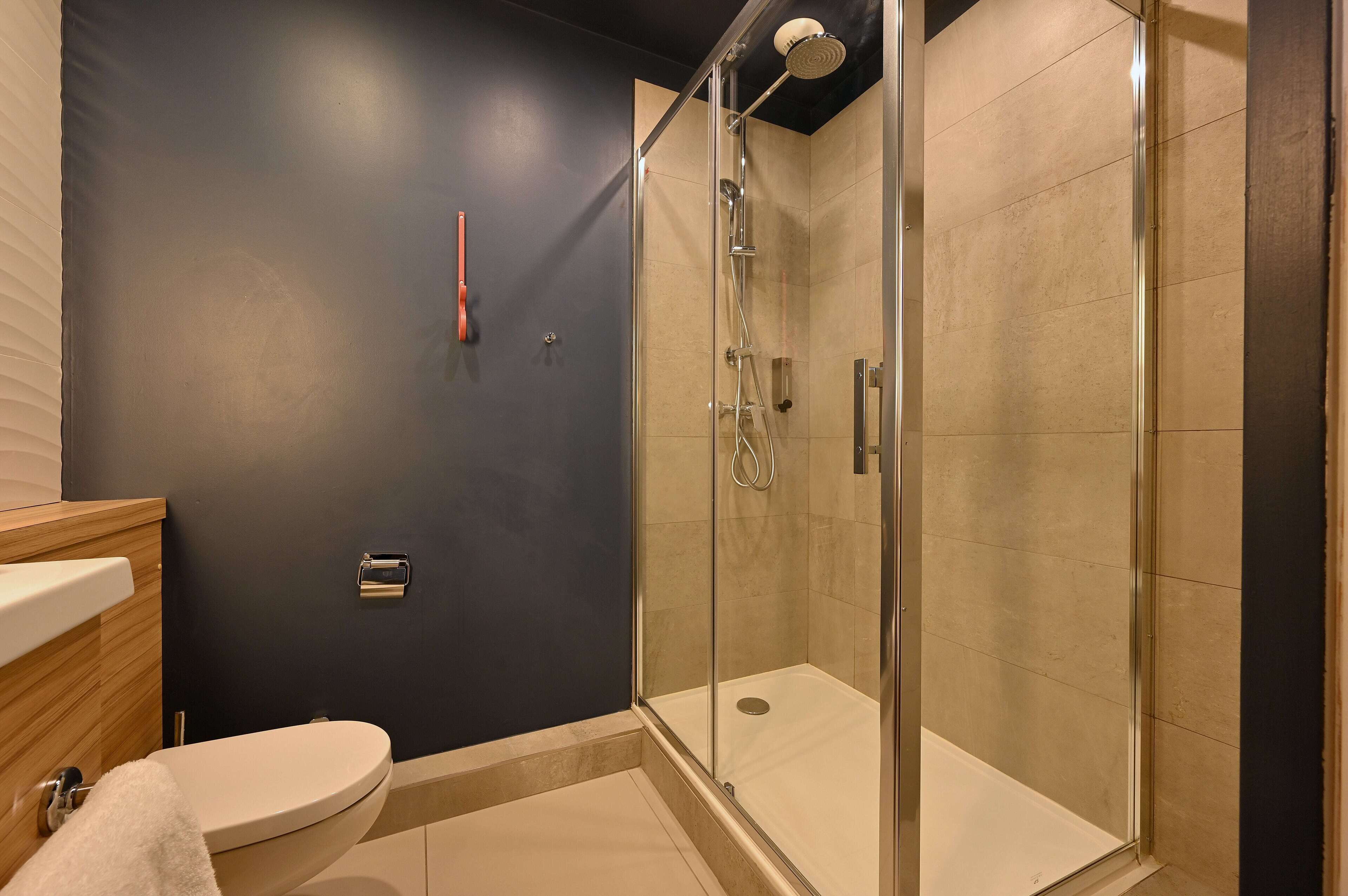 Un baño moderno con ducha acristalada, inodoro y lavamanos.