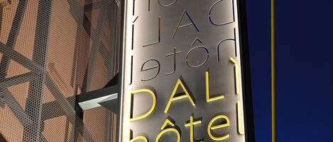 A vertical sign with the name "DAL HOTEL" in illuminated letters.