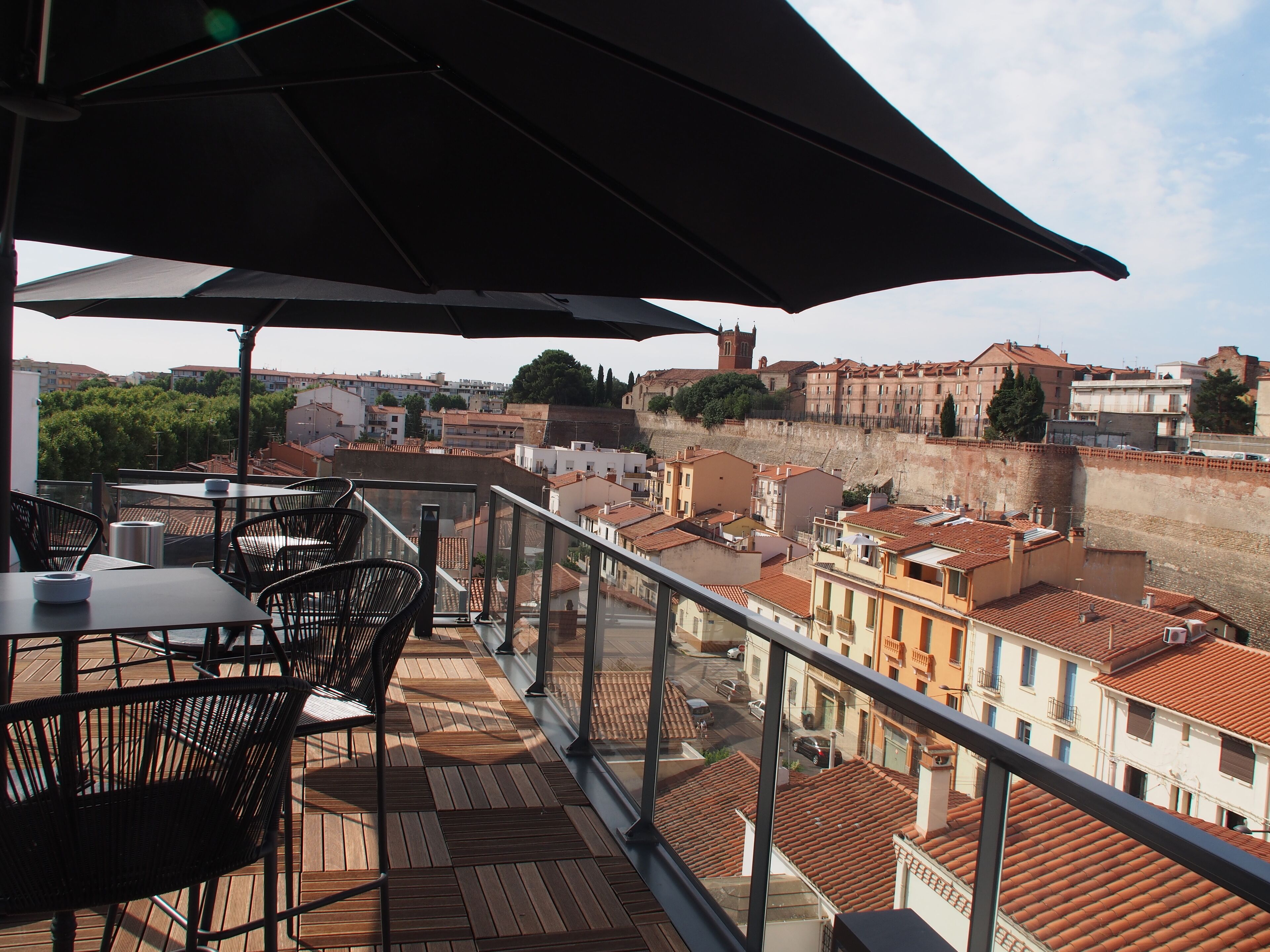 Una terrassa amb taules i caires, amb vista a un paisatge urbà ple d'edificis històrics i un riu.