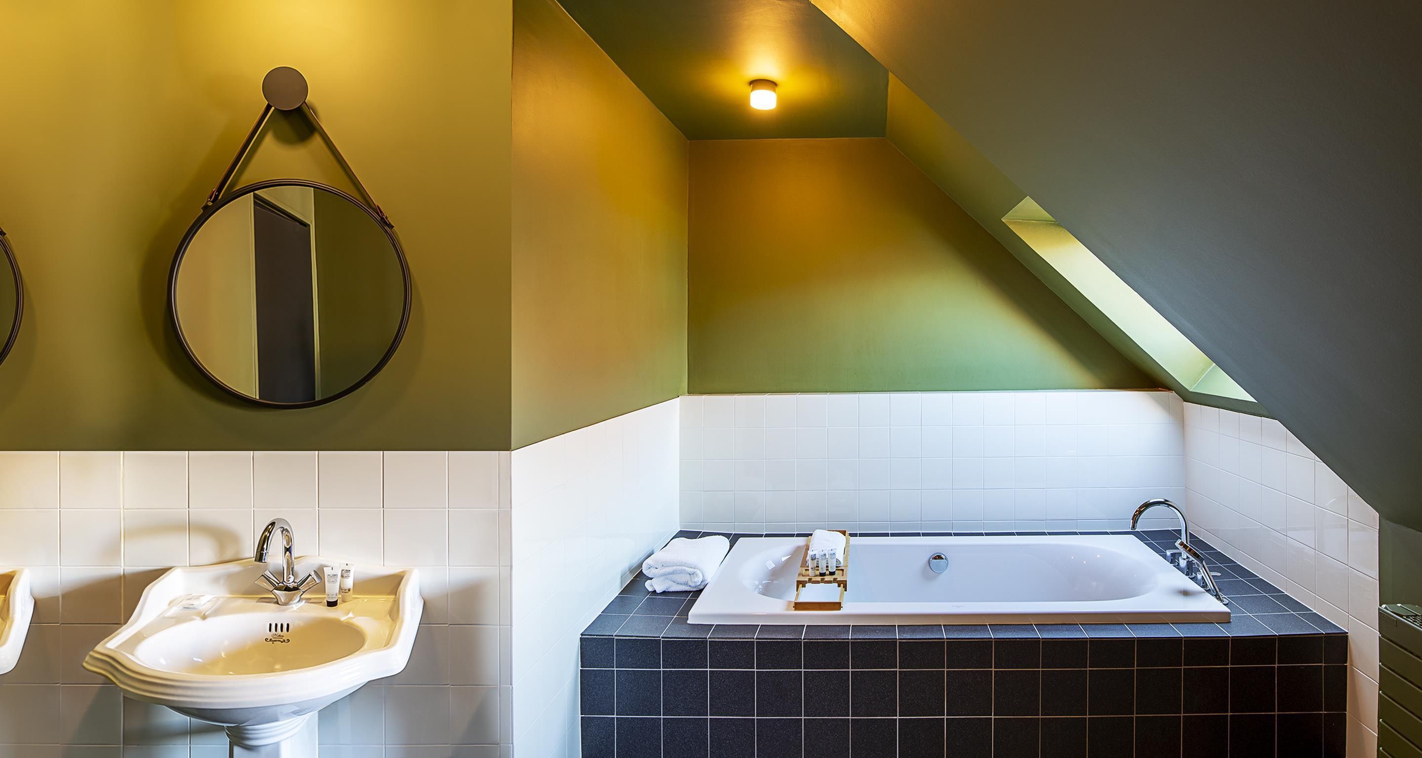 A bathroom with a sink, mirror, and bathtub.