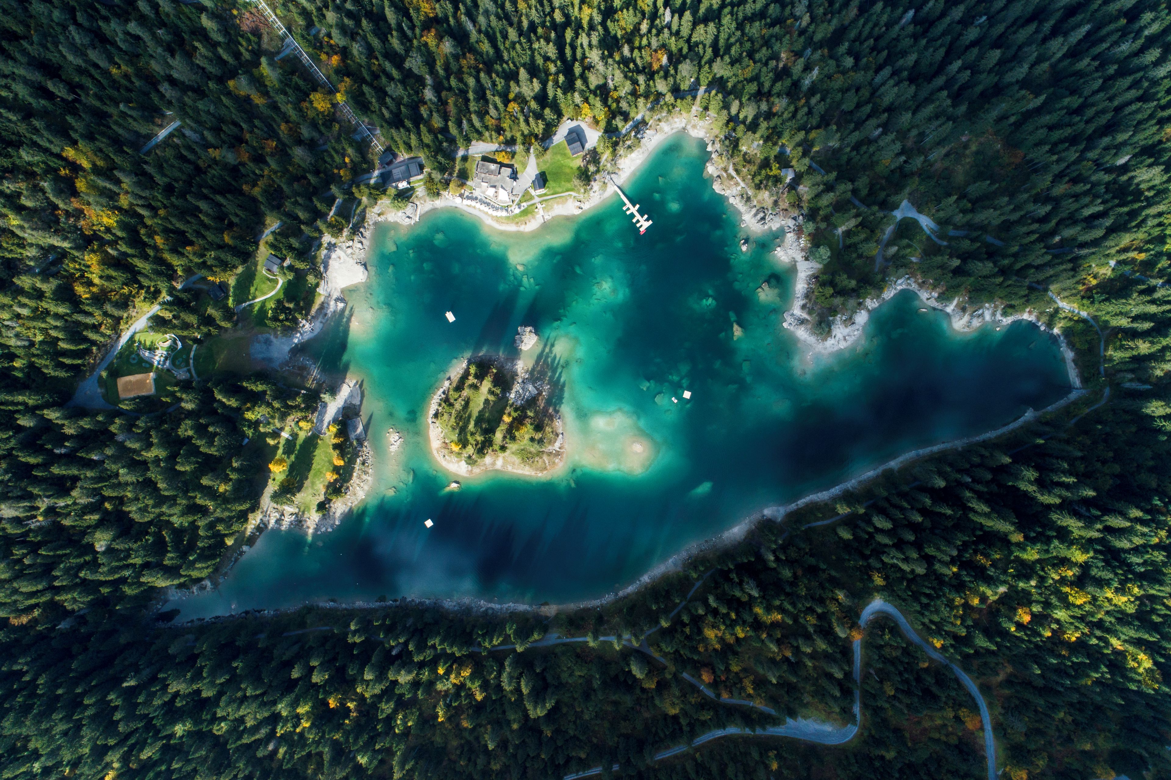 An aerial view of a secluded island with a clear turquoise lake, surrounded by dense forest.