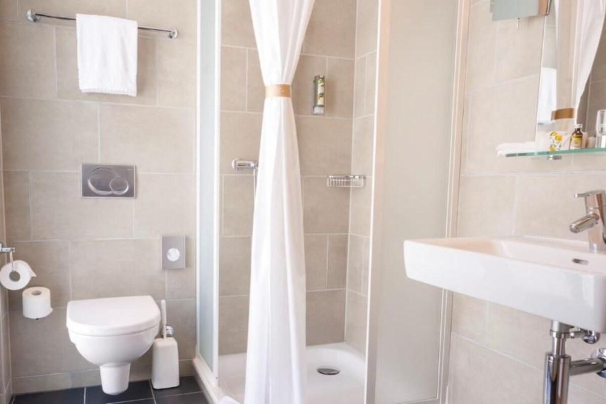 A modern bathroom with a toilet, bidet, shower, and sink.