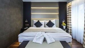 Una habitación de hotel moderna con una cama grande, mesitas de noche y un banco con toallas.