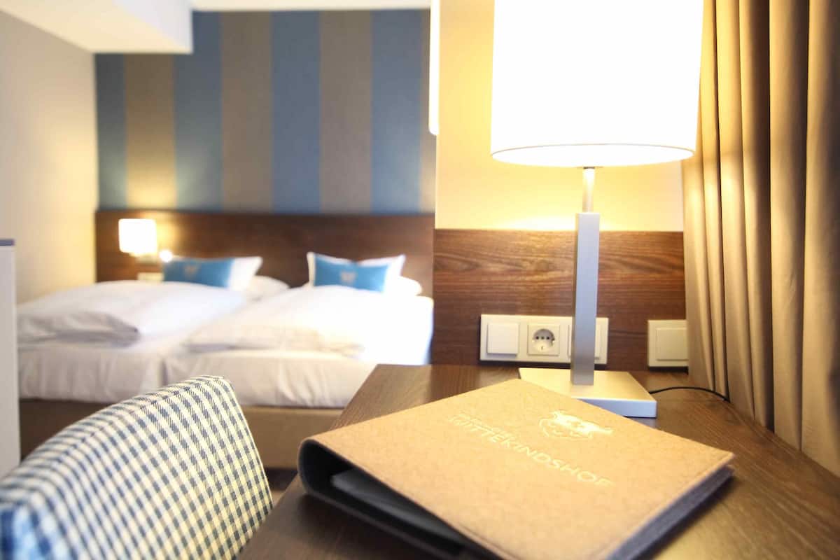 Une chambre d’hôtel avec un lit, un bureau doté d’une lampe et un carnet posé sur le bureau.