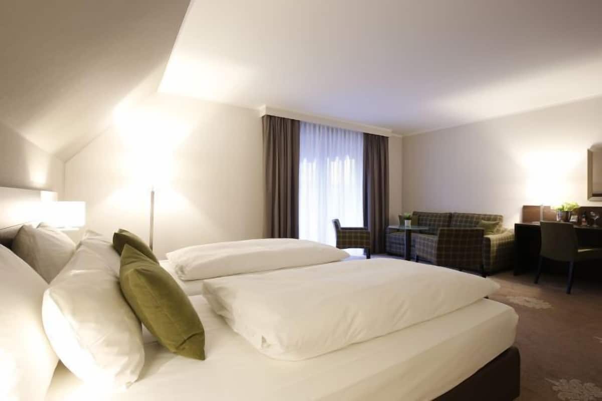 Une chambre d’hôtel avec un grand lit, un bureau, une chaise et un canapé.
