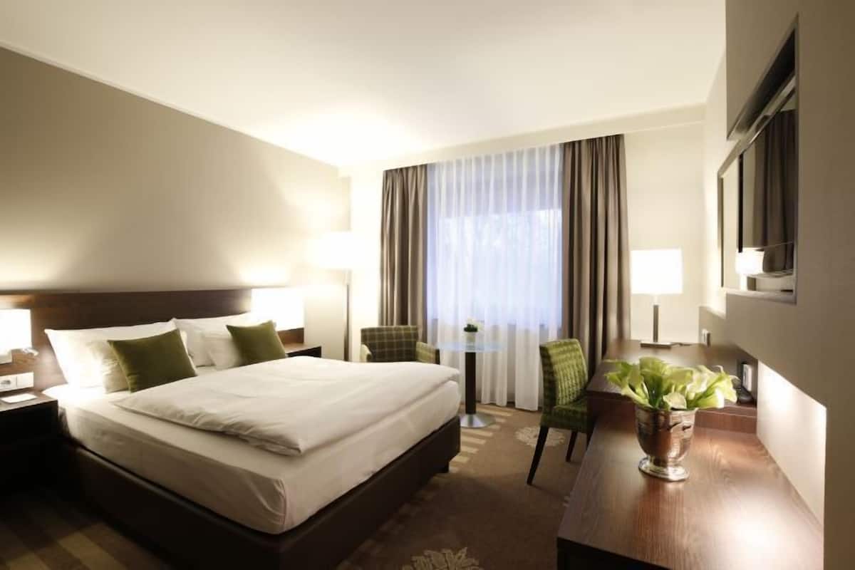 Une chambre d’hôtel avec un grand lit, un bureau, une chaise et un téléviseur.