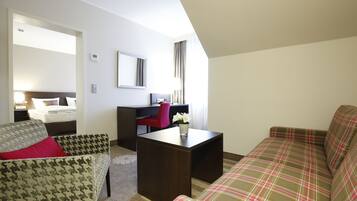 A hotel room with a bed, a desk, a chair, and a sofa.