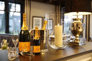Zona de bar con botellas de champán, copas, una vela y una lámpara decorativa.