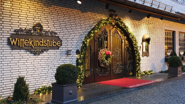 A hotel entrance with a brick facade, a sign reading "Wittekindstube," and a red carpet leading to the door. - Parkhotel Wittekindshof Dortmund (Dortmund)