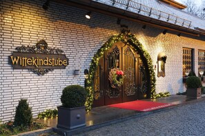 Fachada de hotel de ladrillo, con un letrero que dice "Wittekindstube" y una alfombra roja que lleva a la puerta.