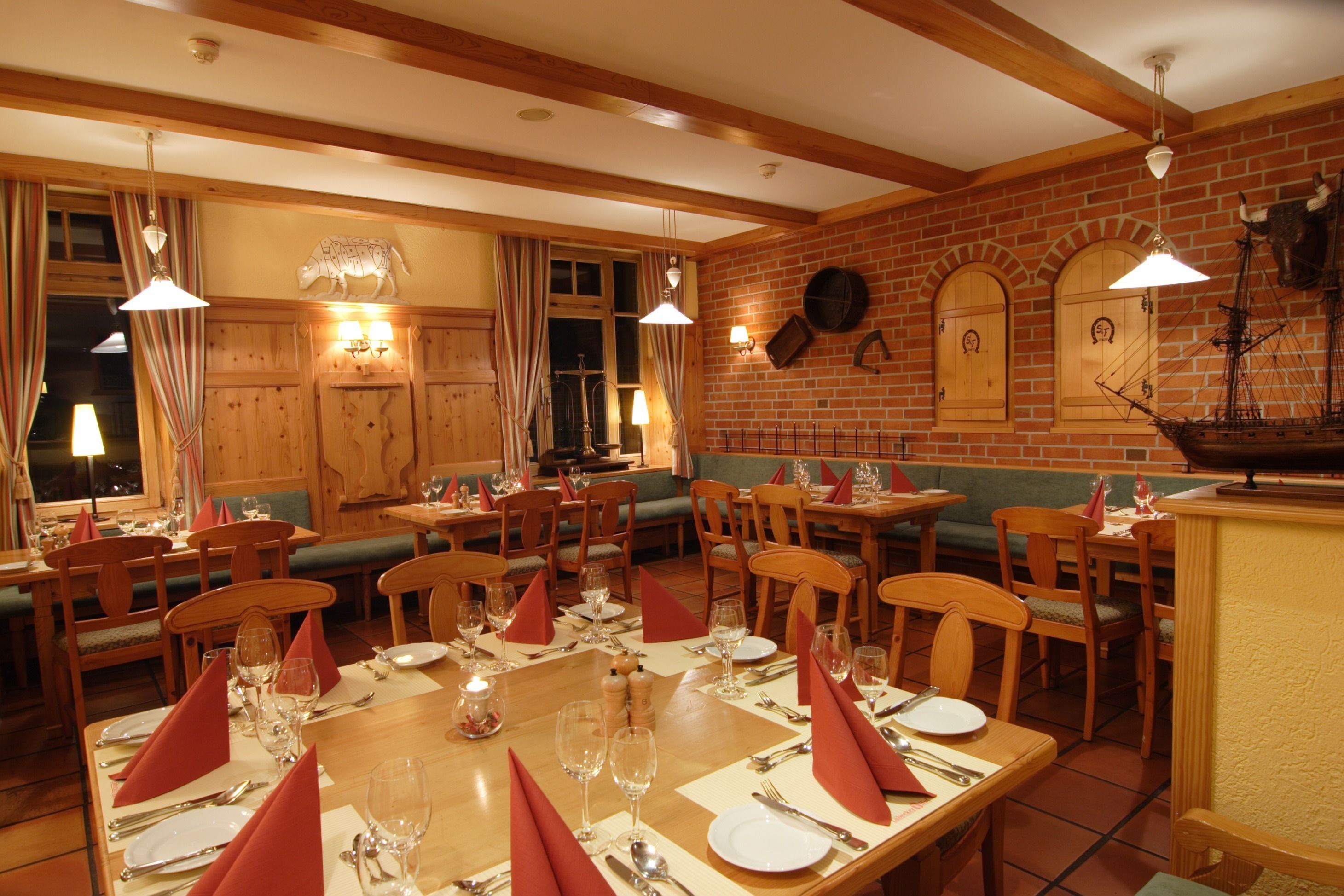Ein Restaurant mit Holztischen und -stühlen, gedeckt mit roten Servietten und Besteck.