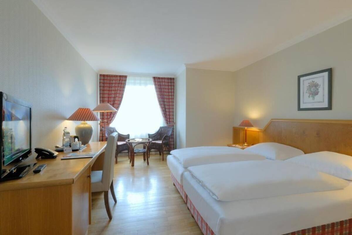 A hotel room with a bed, desk, chair, and a television.