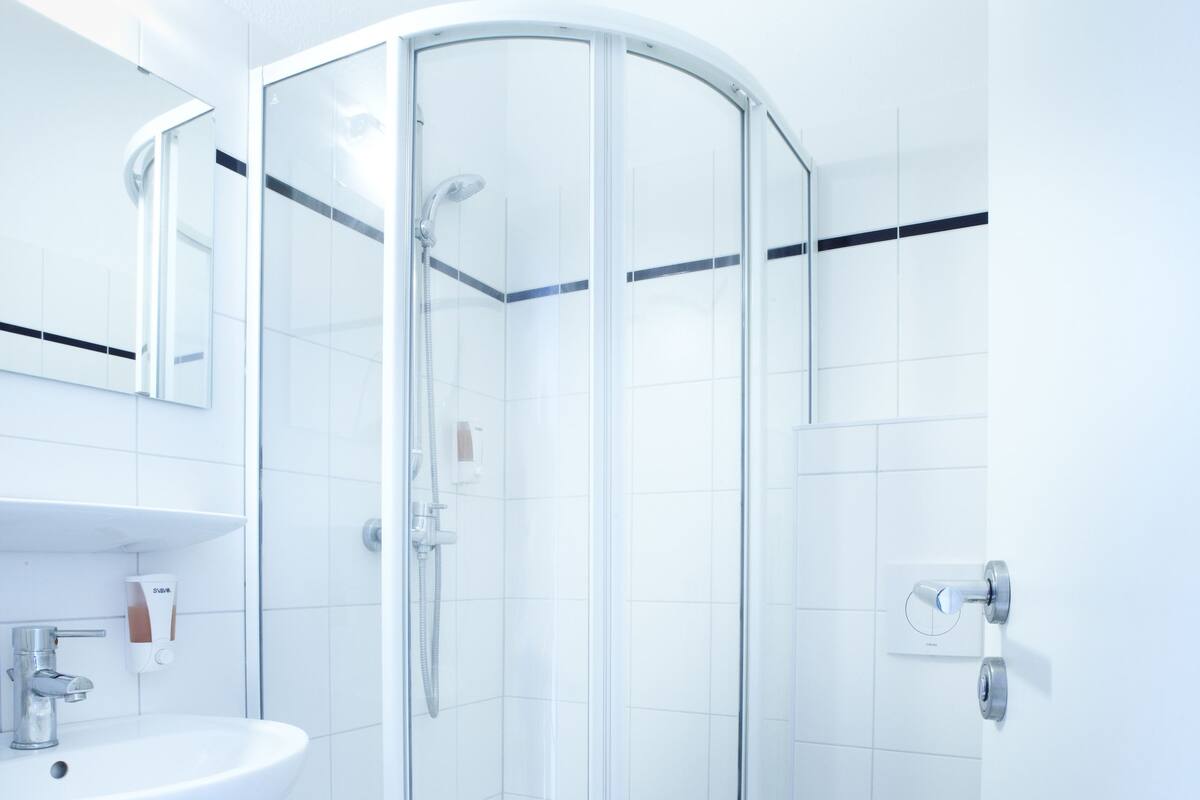 A modern bathroom with a glass shower enclosure, a white sink, and a toilet.