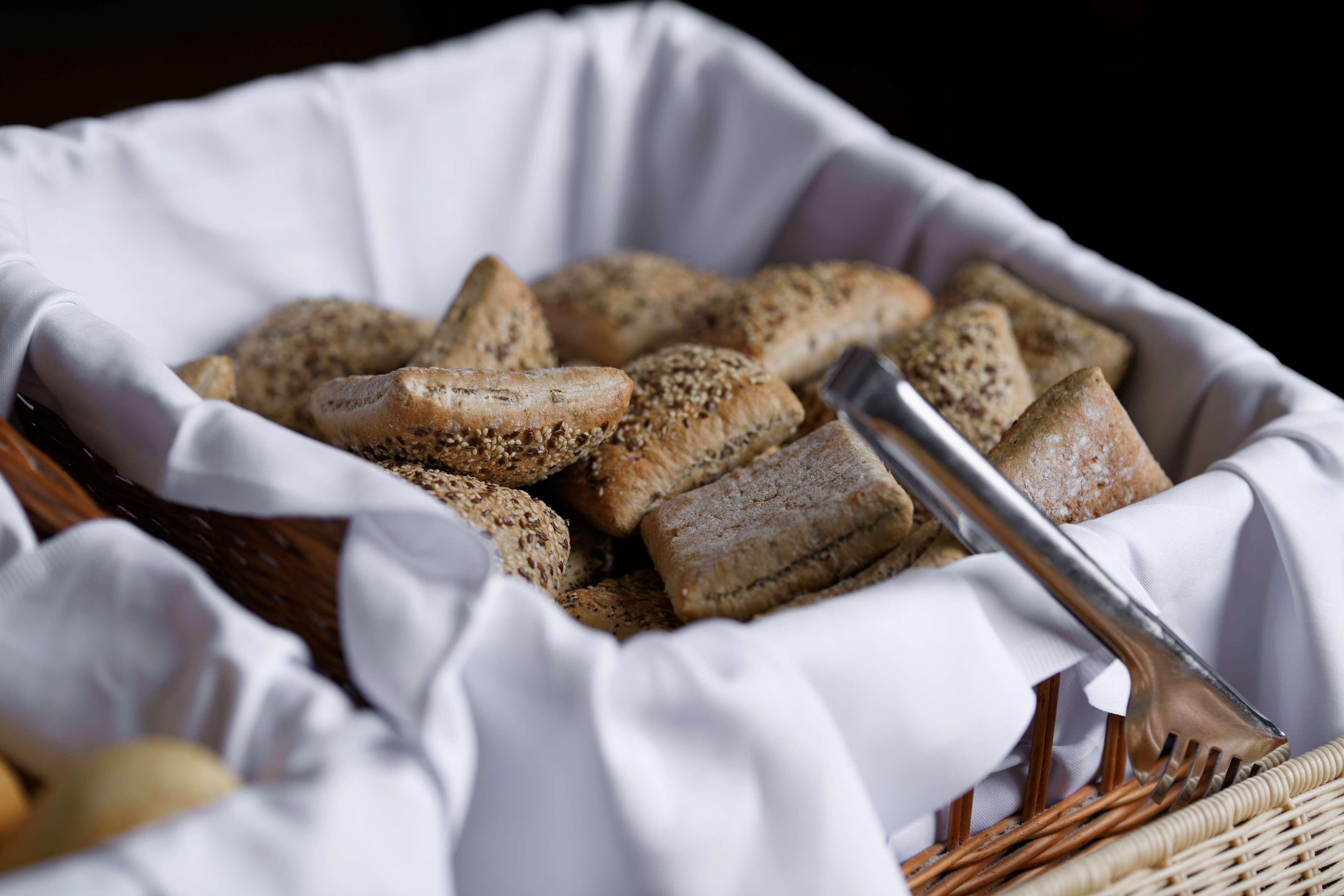 Una cesta con rebanadas de pan de sésamo, acompañada de un tenedor.