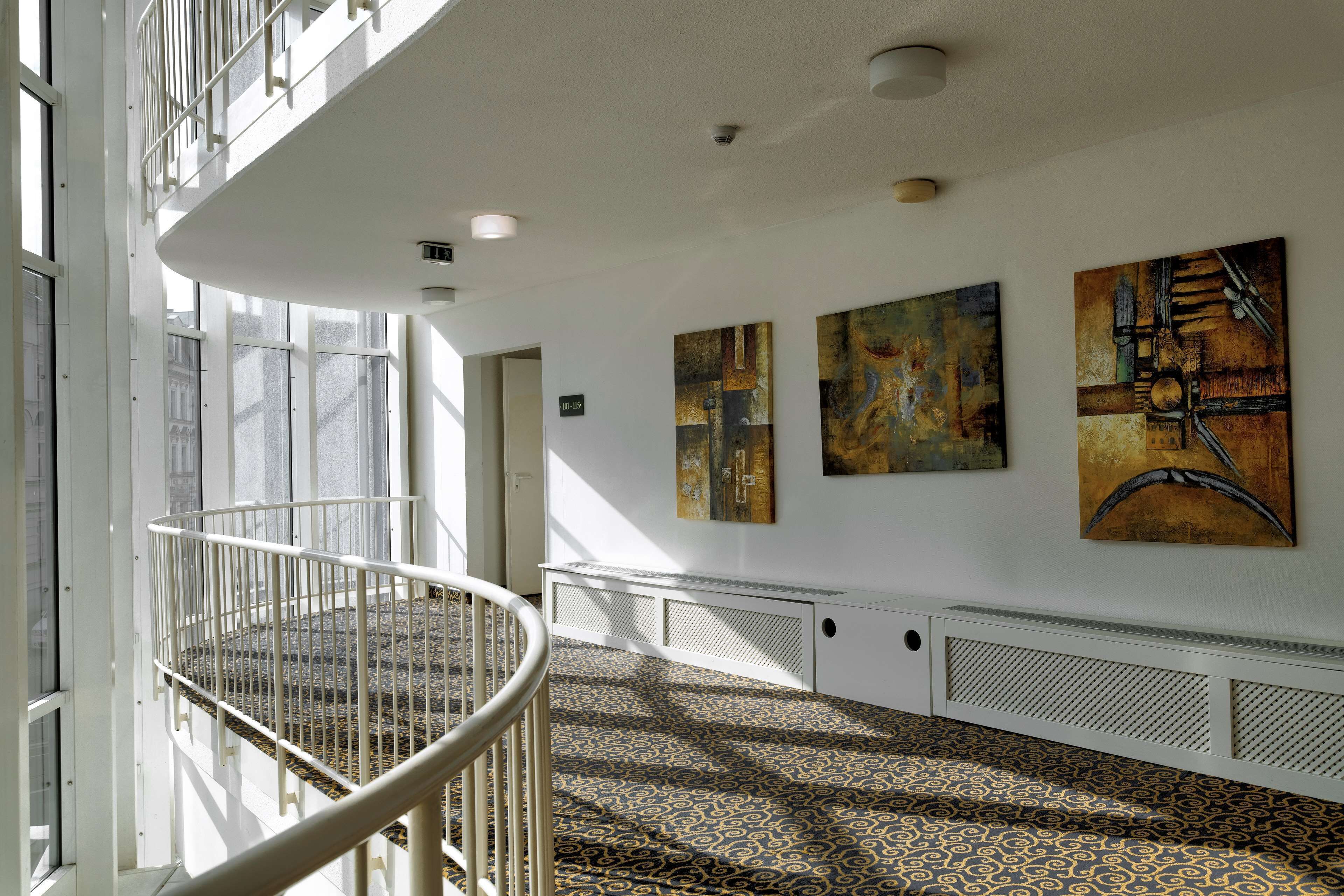 A spacious interior with a high ceiling, a central staircase, and artwork on the walls.