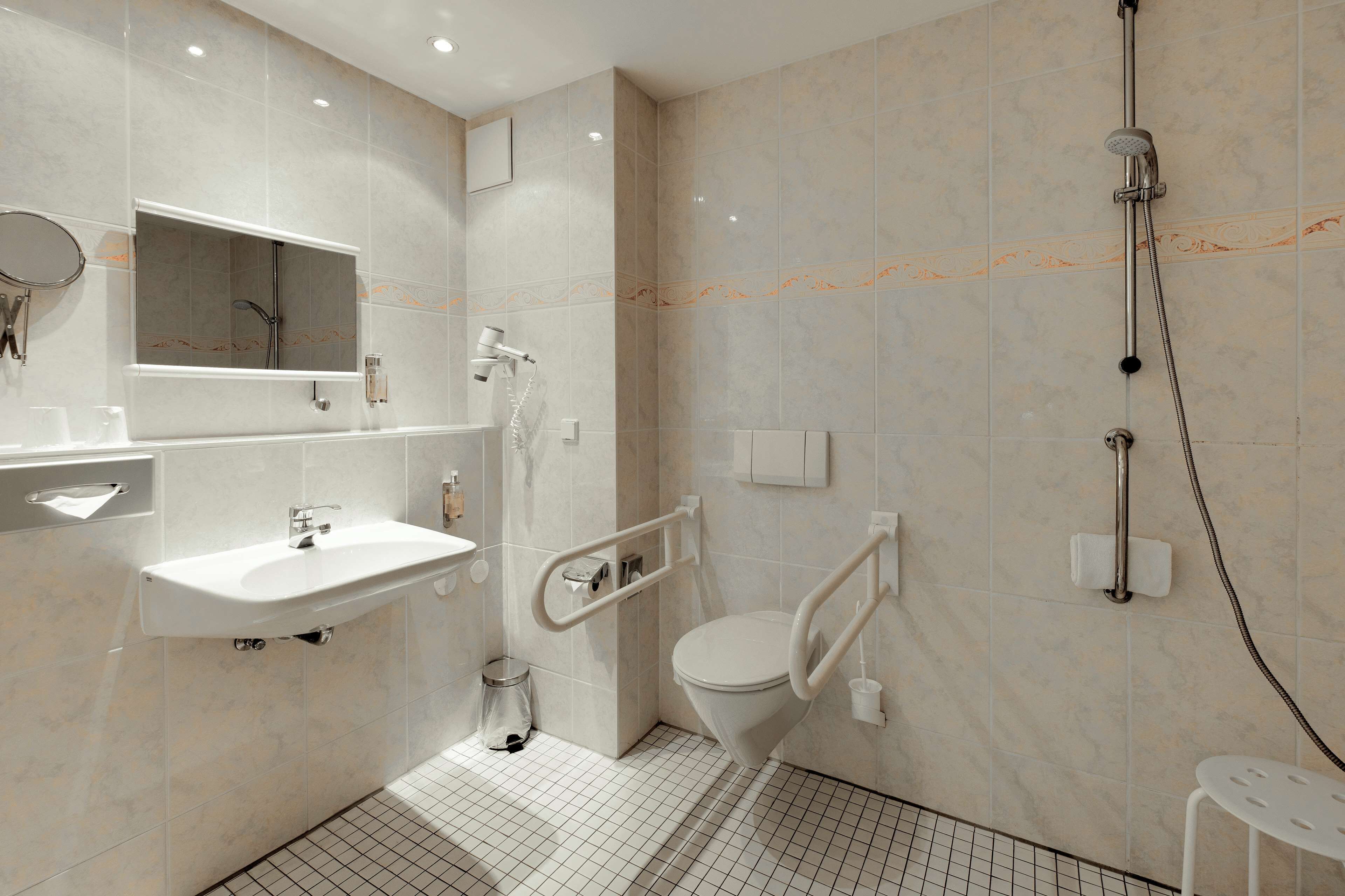 Un baño moderno con lavamanos, espejo, inodoro y ducha.