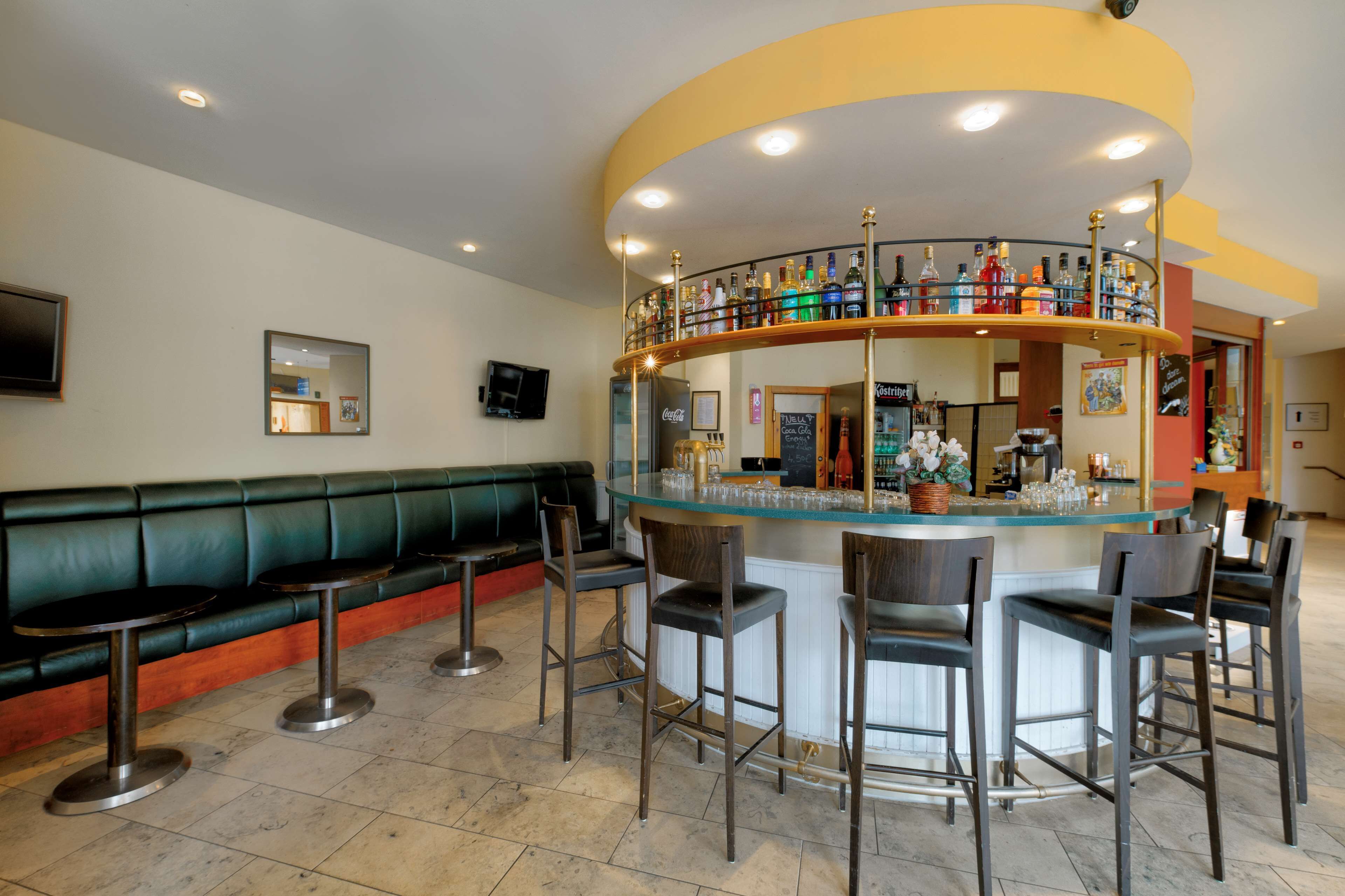 A bar area with a curved counter, multiple stools, and a green cushioned bench.