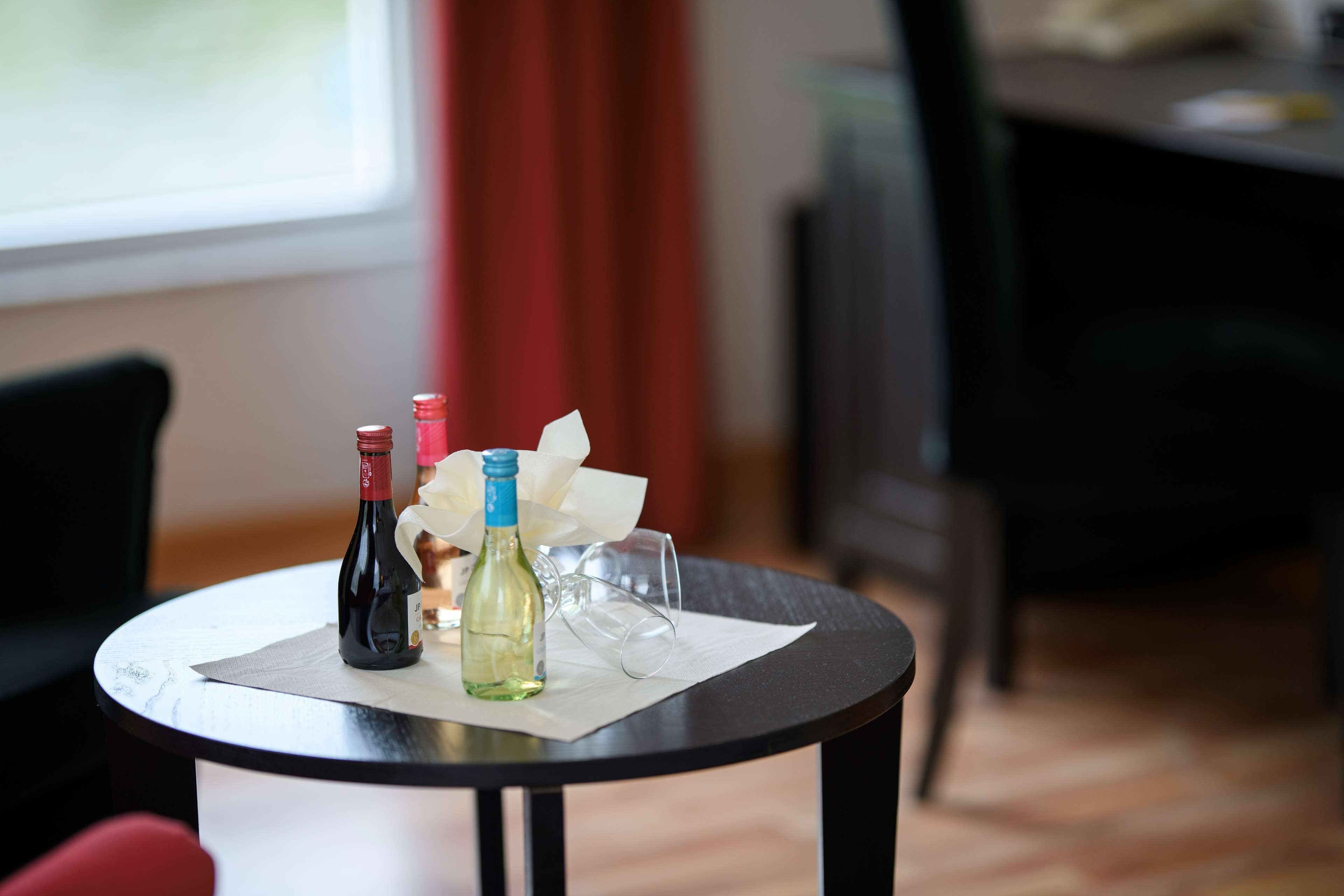 A small round table with two bottles and a glass on a white placemat.