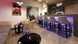 A modern bar area with bar stools, a counter, and a seating area with a sofa and chairs. - Leonardo Hotel Munich City Olympiapark (Munich)