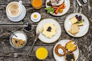 A breakfast setting with various food items and drinks on a wooden table.