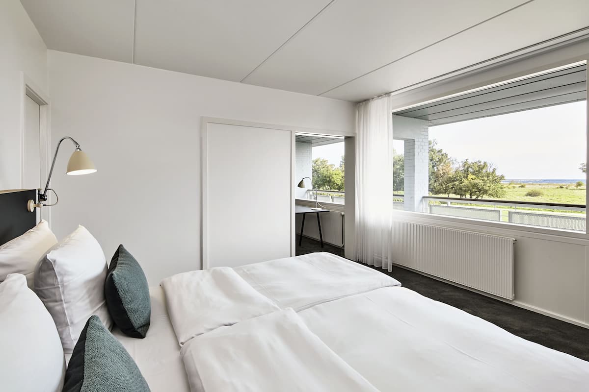 Ein modernes Hotelzimmer mit einem großen Bett, einem Schreibtisch und Blick ins Freie.