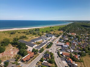 An aerial view of a coastal town with a beach, residential areas, and a large building complex.
