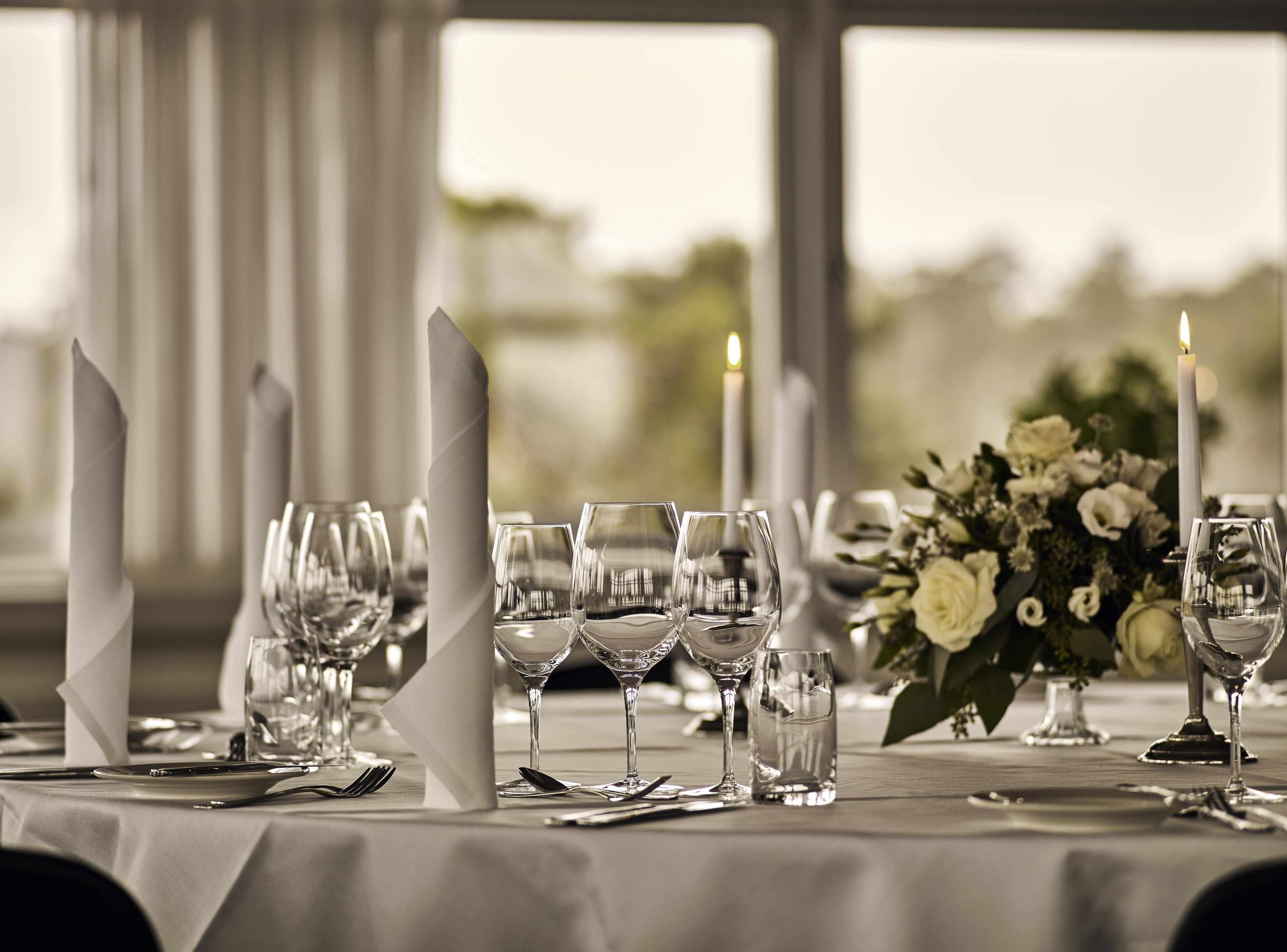 A table set for a formal dining occasion with clear glassware, folded napkins, and a candle.